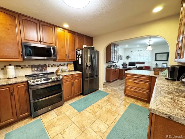 a kitchen with stainless steel appliances kitchen island granite countertop a stove top oven a sink dishwasher a dining table and chairs with wooden floor