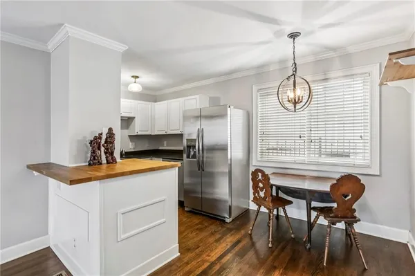 a kitchen with stainless steel appliances granite countertop a dining table chairs and a refrigerator