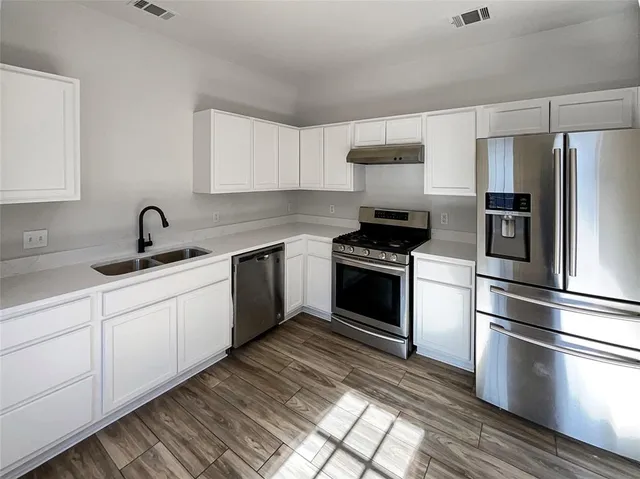 a kitchen with granite countertop a sink stainless steel appliances and cabinets