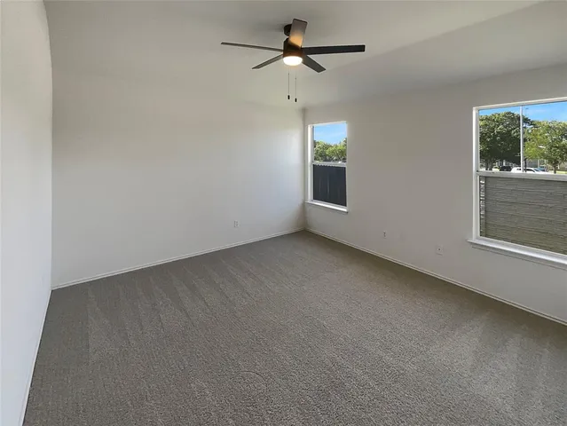an empty room with windows and fan