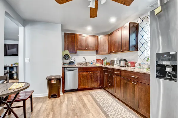 a kitchen with stainless steel appliances granite countertop a sink dishwasher a stove a refrigerator and cabinets with wooden floor