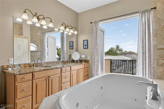 a bathroom with a granite countertop sink a large mirror and a bathtub next to a window
