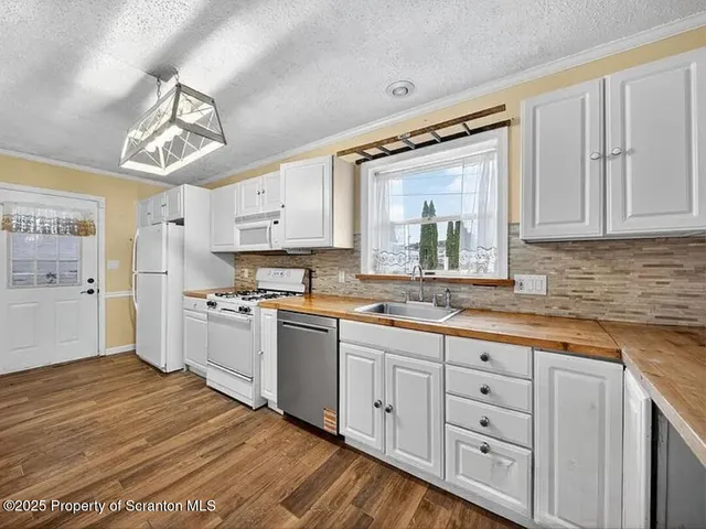 a kitchen with white cabinets a sink dishwasher and a stove with wooden floor
