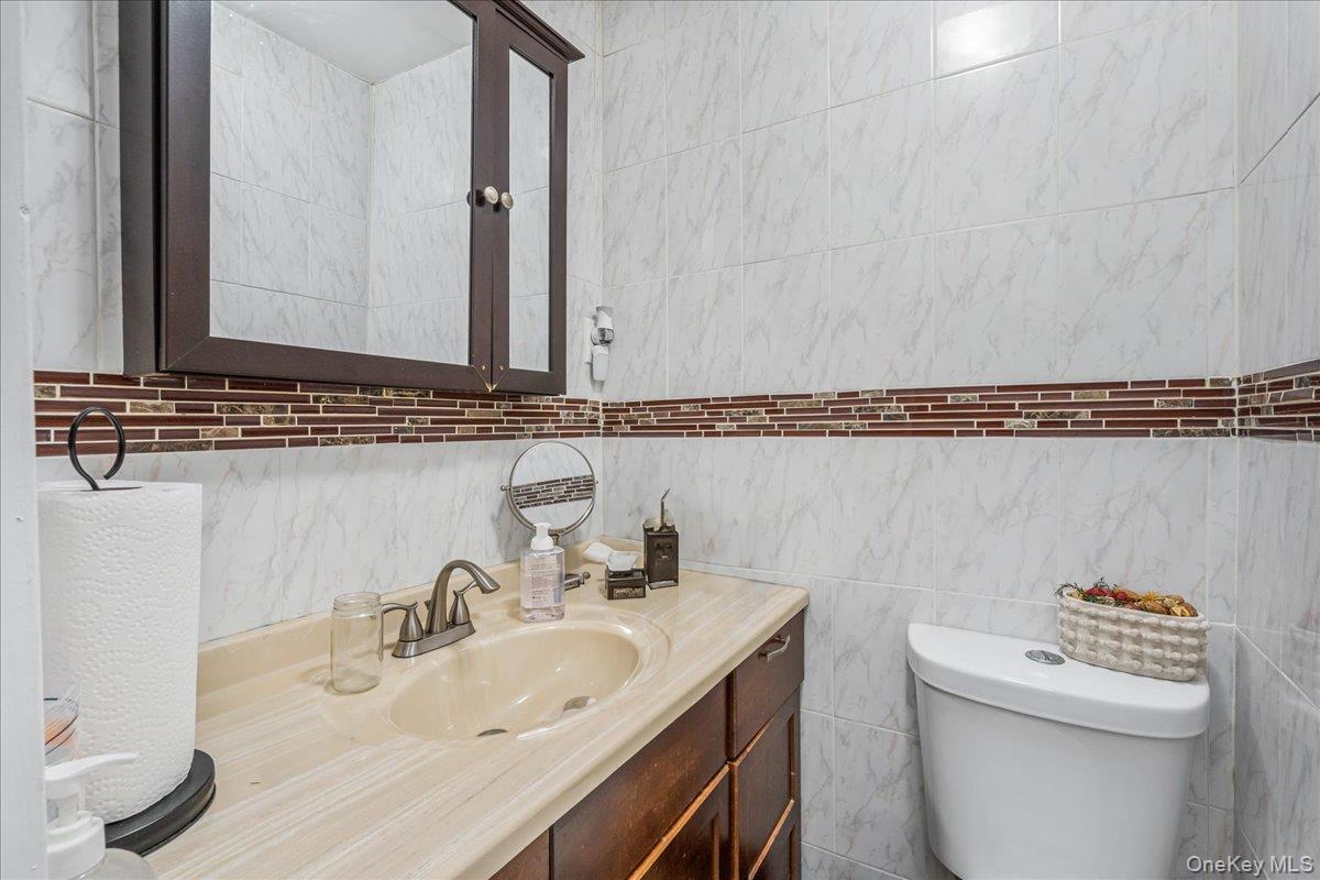 132-14 Horace Harding Expressway Queens, NY 11367 - Photo 20 of 25 Half bathroom featuring vanity and tile walls