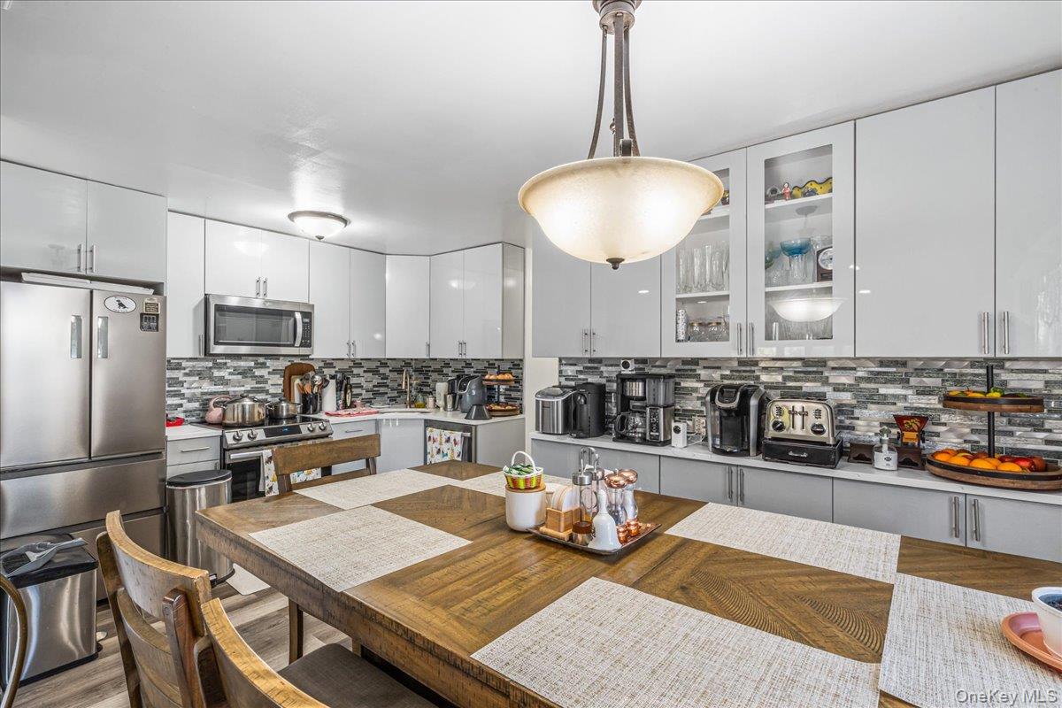 132-14 Horace Harding Expressway Queens, NY 11367 - Photo 23 of 25 Kitchen with appliances with stainless steel finishes, pendant lighting, white cabinets, and decorative backsplash