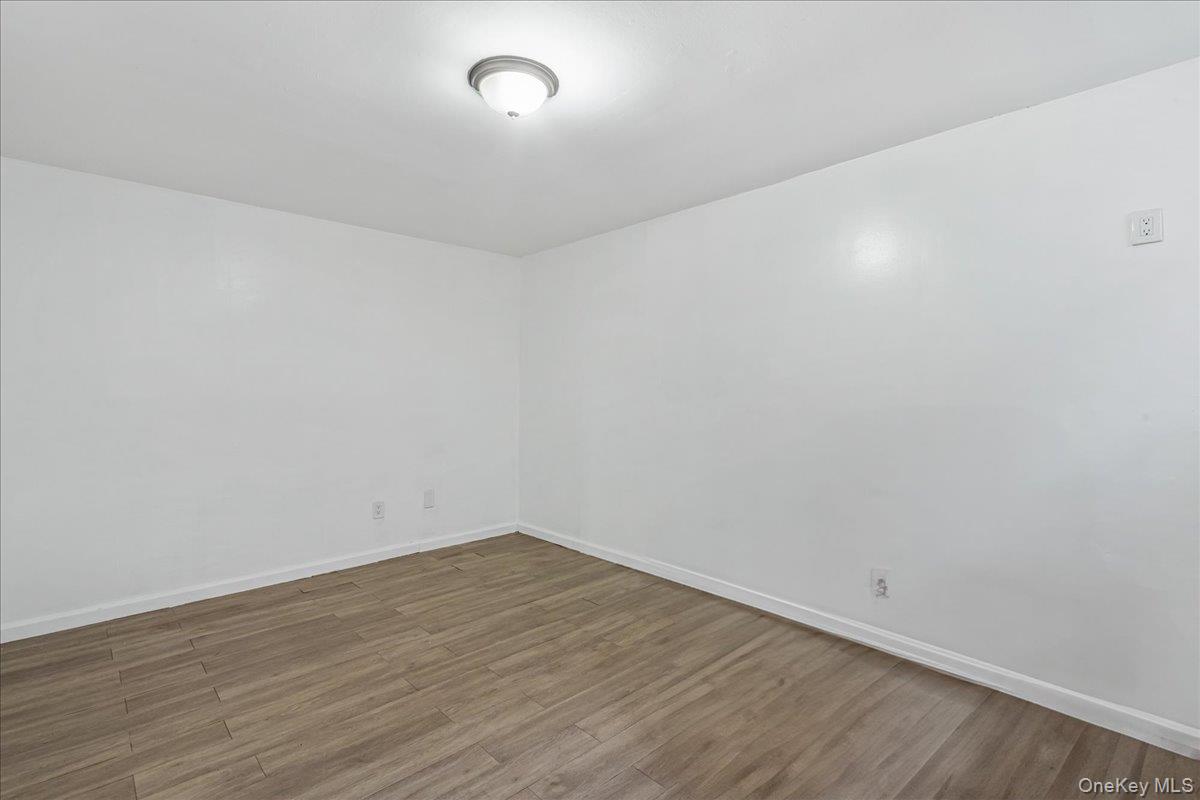 132-14 Horace Harding Expressway Queens, NY 11367 - Photo 8 of 25 Unfurnished room with wood finished floors and baseboards