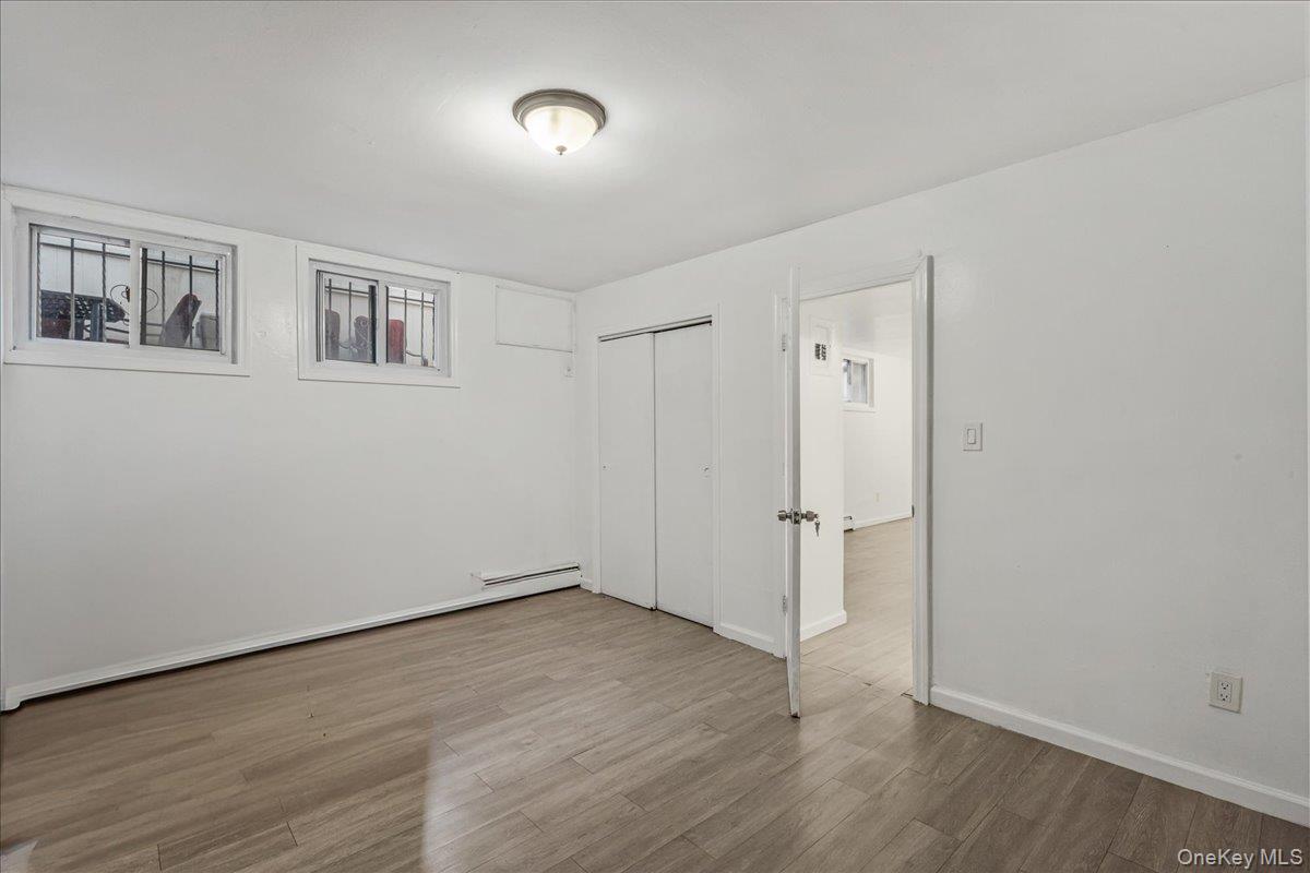 132-14 Horace Harding Expressway Queens, NY 11367 - Photo 9 of 25 Unfurnished bedroom featuring wood finished floors, a closet, and a baseboard heating unit