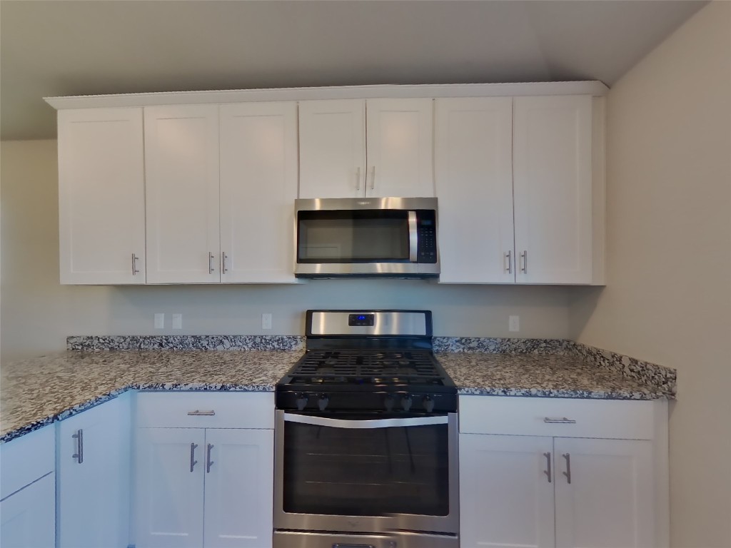 5205 Sidesaddle Drive Georgetown, TX 78626 - Photo 4 of 26 Kitchen with appliances with stainless steel finishes, white cabinetry, and light stone countertops
