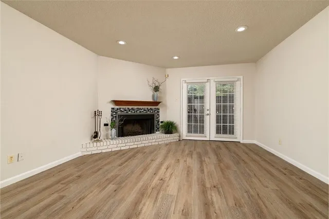 a view of an empty room with wooden floor fireplace and a window