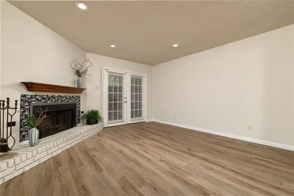 a view of an empty room with wooden floor fireplace and a window