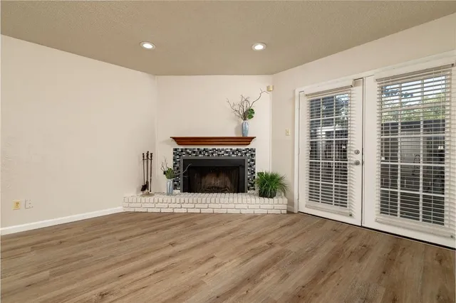 a view of an empty room with wooden floor fireplace and a window