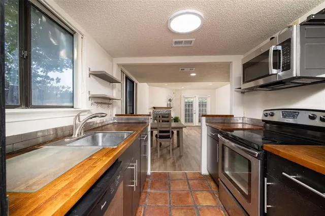 a kitchen with stainless steel appliances granite countertop a stove a sink and a microwave