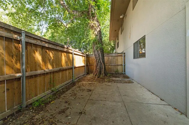 a view of backyard with large tree and wooden fence