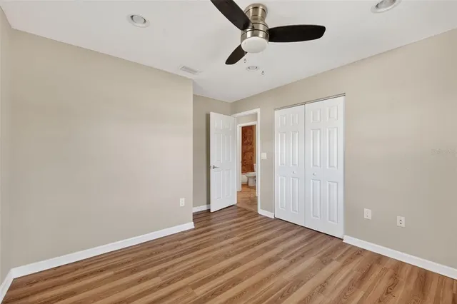 an empty room with wooden floor ceiling fan and windows