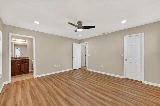 a view of empty room with wooden floor and ceiling fan
