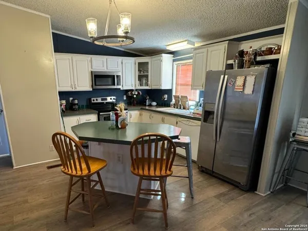 a kitchen with stainless steel appliances granite countertop a refrigerator a stove a sink dishwasher a dining table and chairs with wooden floor