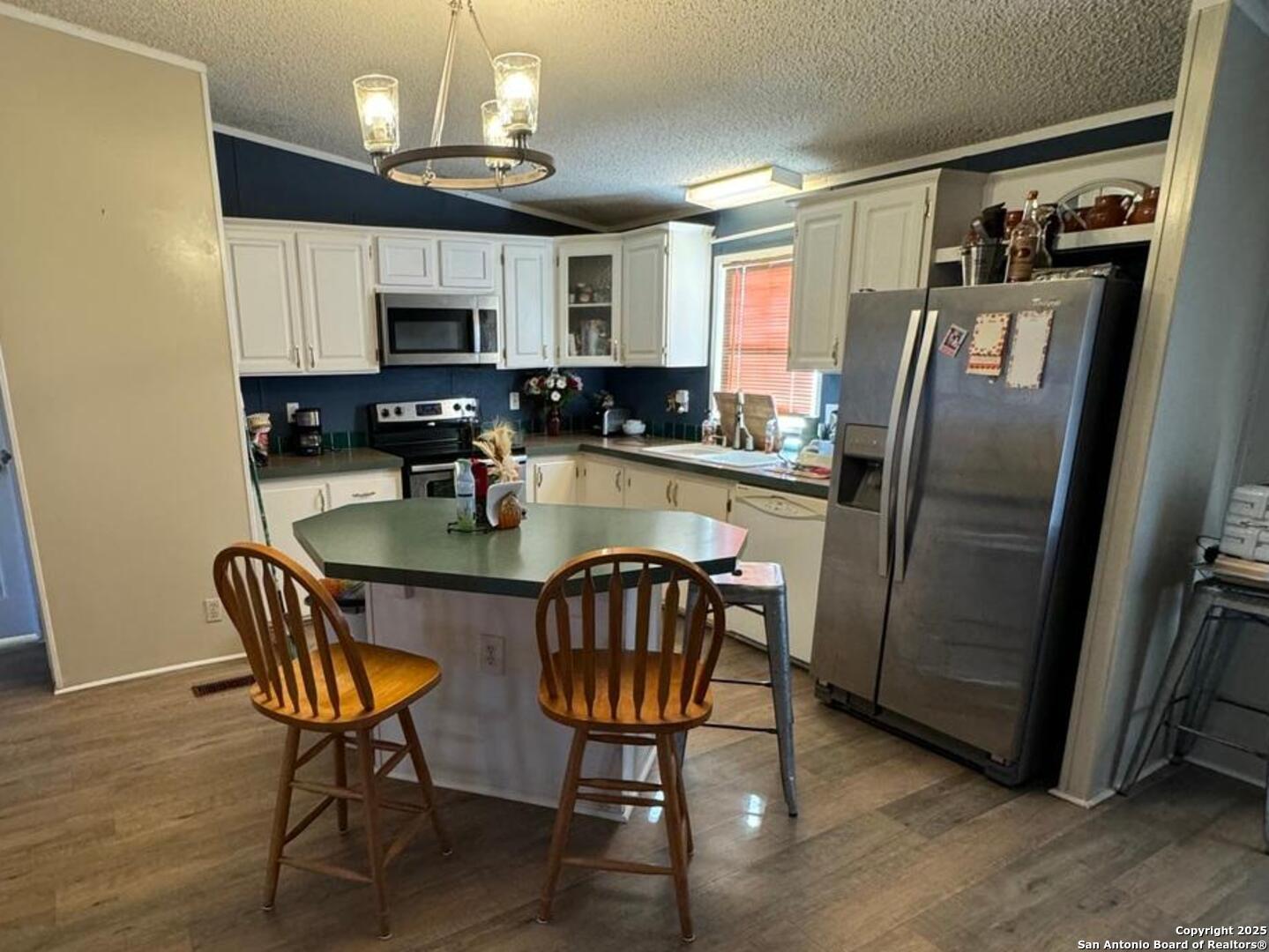 672 North Main Street Cotulla, TX 78014 - Photo 2 of 6 a kitchen with stainless steel appliances granite countertop a refrigerator a stove a sink dishwasher a dining table and chairs with wooden floor
