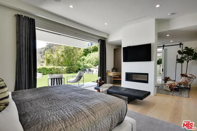 a spacious bedroom with a bed and a flat screen tv