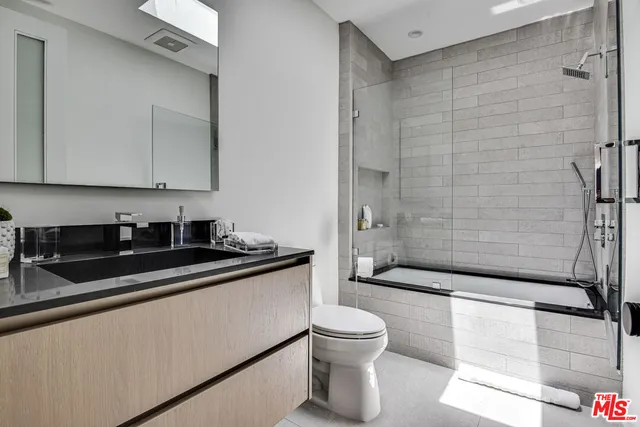 a bathroom with a granite countertop sink a toilet and shower