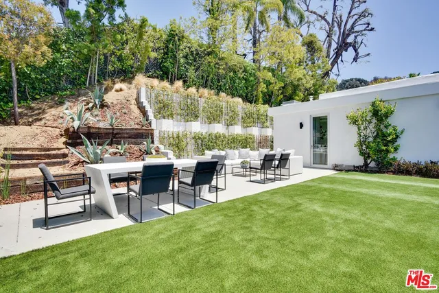 a view of a patio with table and chairs potted plants and large tree