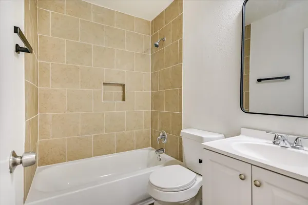 a bathroom with a bathtub shower sink mirror vanity and toilet