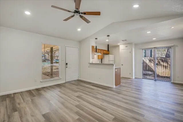 a view of an empty room with wooden floor and a ceiling fan