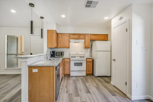 a kitchen with stainless steel appliances granite countertop a refrigerator a stove and a sink with wooden floor