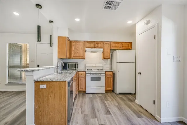 a kitchen with stainless steel appliances granite countertop a refrigerator a stove and a wooden floors