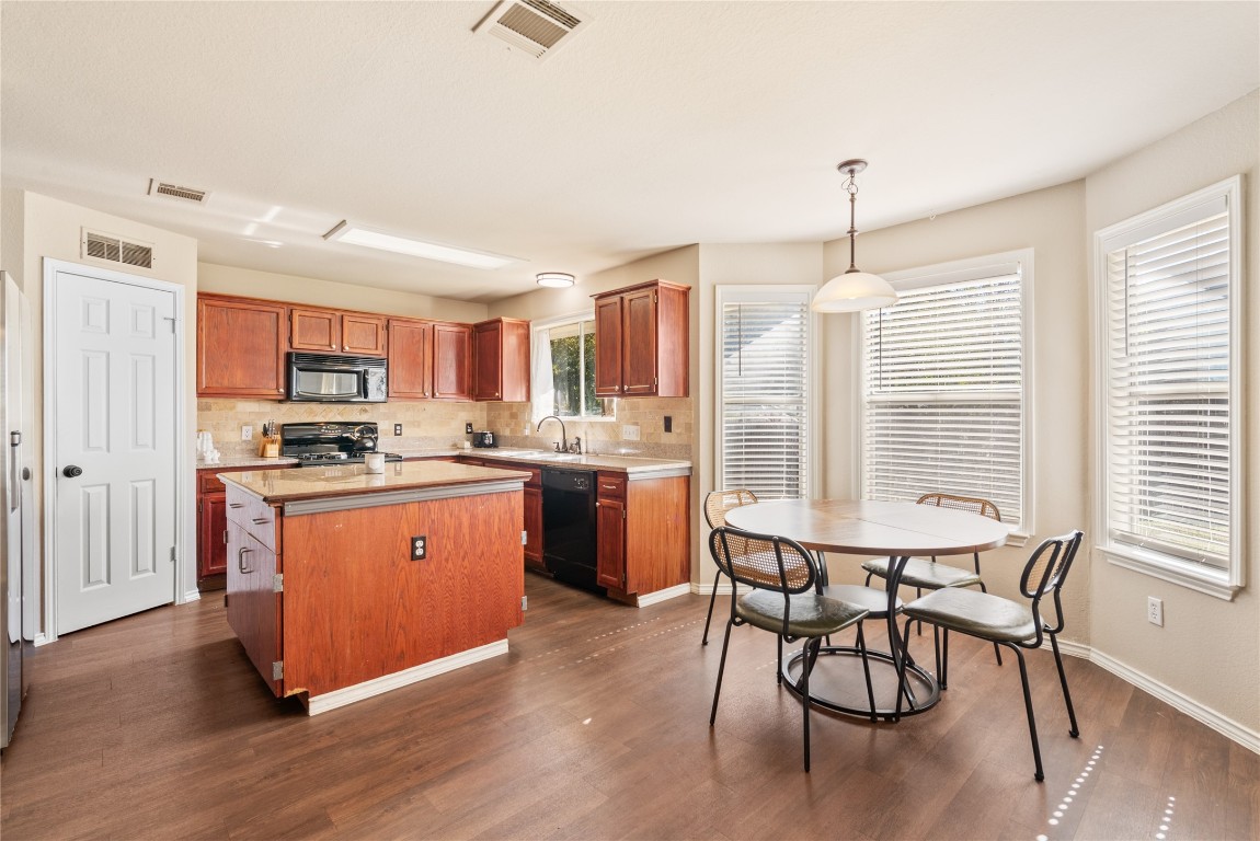 1111 Pathfinder Way Round Rock, TX 78665 - Photo 25 of 40 a kitchen with stainless steel appliances granite countertop a stove top oven a sink dishwasher a dining table and chairs with wooden floor