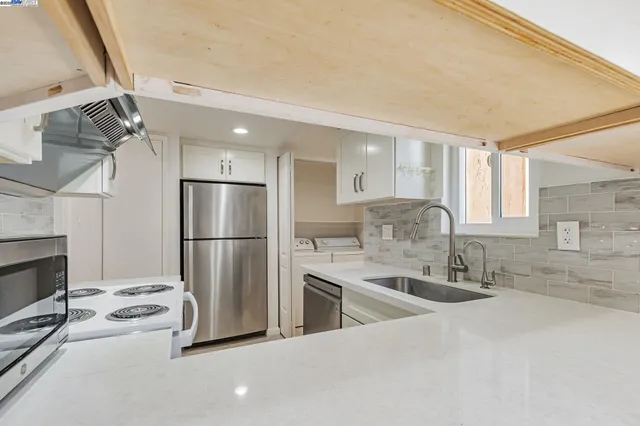 a view of a kitchen with kitchen island a sink wooden floor and stainless steel appliances