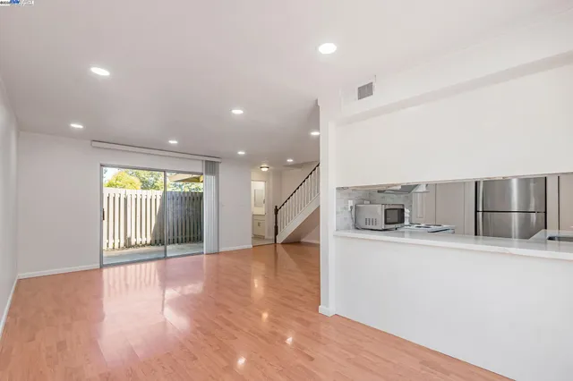 a view of a kitchen with kitchen island a sink wooden floor and stainless steel appliances