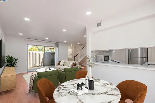 a living room with furniture kitchen view and large windows