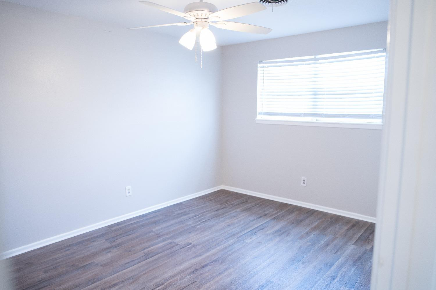 5522 13th Street, Unit A Lubbock, TX 79416 - Photo 7 of 11 an empty room with wooden floor and windows