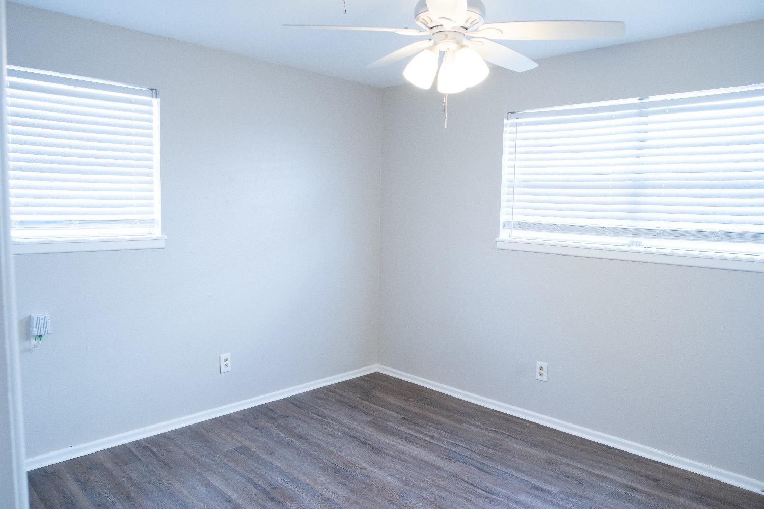5522 13th Street, Unit A Lubbock, TX 79416 - Photo 10 of 11 an empty room with wooden floor fan and windows