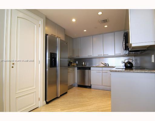 101 Ocean Drive, Unit 807 Miami Beach, FL 33139 - Photo 6 of 8 a kitchen with a refrigerator and white cabinets