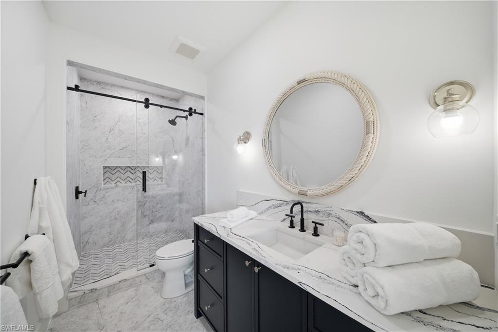 82 9th Street South, Unit 303 Naples, FL 34102 - Photo 14 of 26 a bathroom with a granite countertop sink mirror vanity and toilet