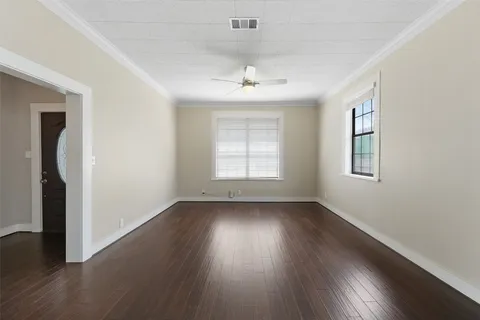 an empty room with wooden floor chandelier and windows