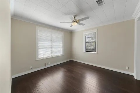 an empty room with wooden floor ceiling fan and windows