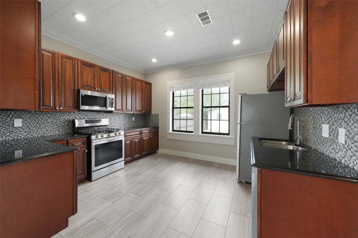 309 Pecore Street Houston, TX 77009 - Photo 21 of 45 a kitchen with granite countertop a stove top oven a sink dishwasher and a refrigerator with wooden cabinets