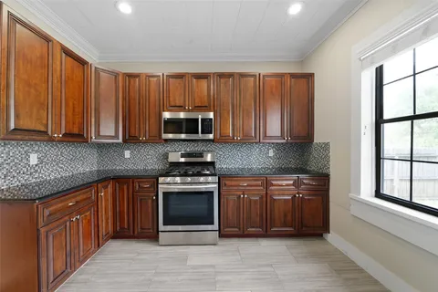 a kitchen with stainless steel appliances granite countertop wooden cabinets a sink and a stove