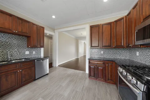 a kitchen with stainless steel appliances granite countertop wooden cabinets a stove top oven a sink and dishwasher