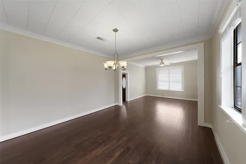 a view of a room with wooden floor chandelier and windows