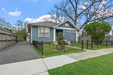 a view of a house with a small yard and a large tree