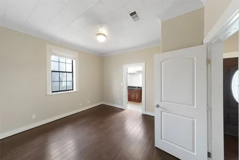 an empty room with wooden floor cabinet and windows
