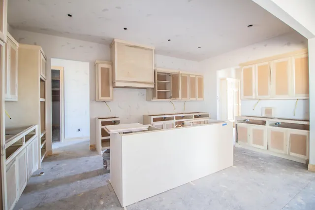 a kitchen with a stove a refrigerator and white cabinets