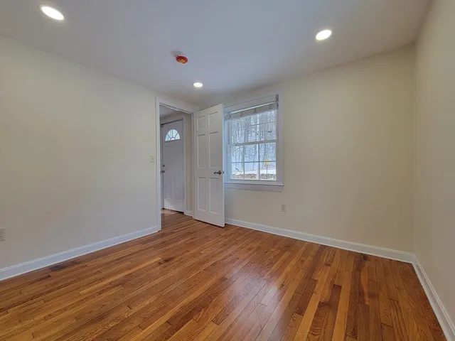 a view of an empty room with wooden floor and a window