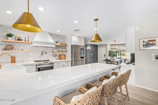 a large kitchen with stainless steel appliances kitchen island granite countertop a table and chairs in it