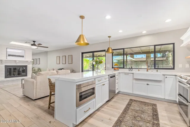 a kitchen that has a lot of white cabinets and stainless steel appliances