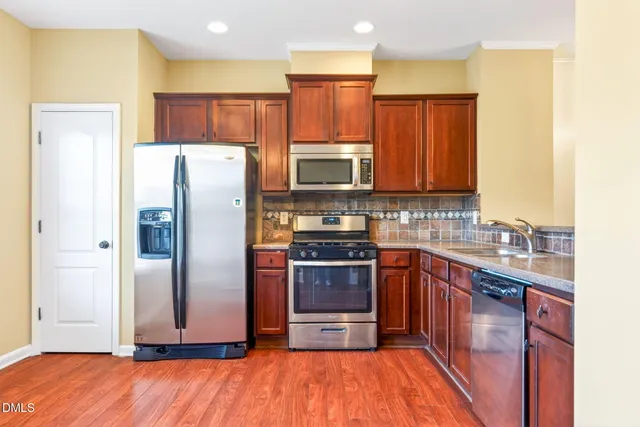 a open kitchen with stainless steel appliances granite countertop a refrigerator and a sink