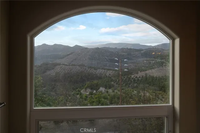 a view of an empty room with a window and a kitchen